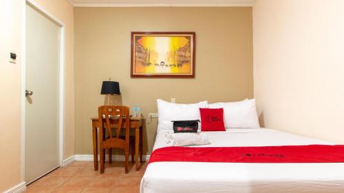 a bedroom with a bed and a desk with a red blanket at RedDoorz @ Downtown Tacloban in Tacloban