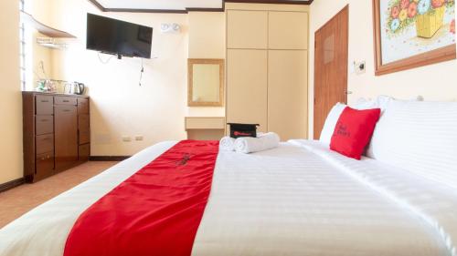 a bedroom with a large white bed with red pillows at RedDoorz @ Downtown Tacloban in Tacloban