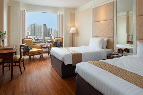 a hotel room with two beds and a desk at The Emerald Hotel in Bangkok