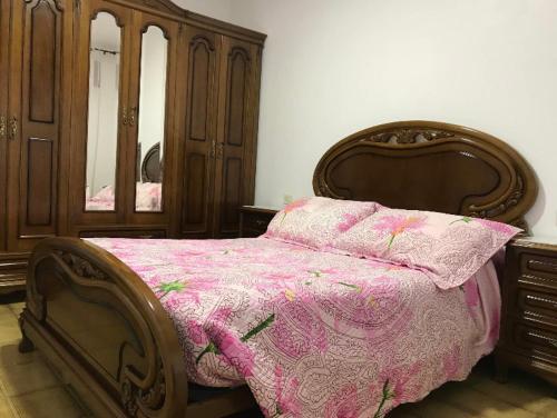 a bedroom with a wooden bed with a pink comforter at Casa de Campo en Sardiñeiro de Arriba in Finisterre