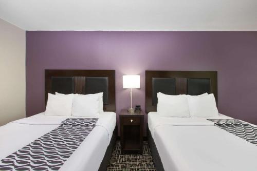 two beds in a hotel room with purple walls at La Quinta by Wyndham Blue Springs in Blue Springs