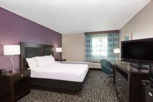 a hotel room with a bed and a flat screen tv at La Quinta by Wyndham Blue Springs in Blue Springs
