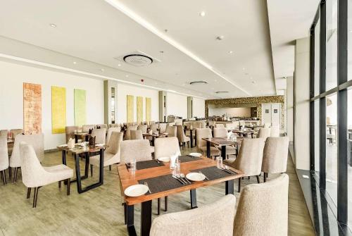 a restaurant with tables and chairs in a room at Ramada by Wyndham Bengaluru Yelahanka in Yelahanka