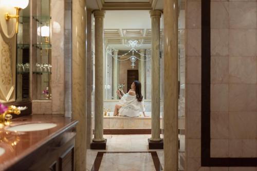 The Emerald Hotel - SHA Extra Plus في بانكوك: امرأة في الحمام تنظر إلى نفسها في المرآة