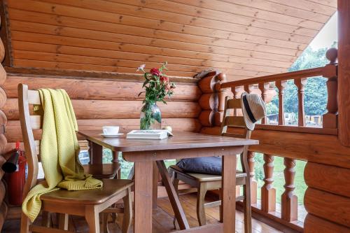 a wooden table and chairs with a vase of flowers on a porch at Tourist Complex belaya Reka Dakhovskaya in Dakhovskaya