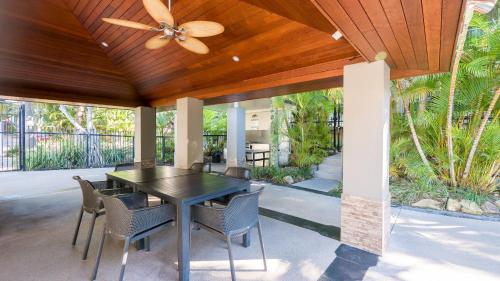 un patio con ventilador de techo, mesa y sillas en Currumbin Sands On The Beach, en Gold Coast