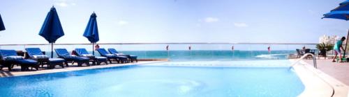 a swimming pool with blue chairs and umbrellas at Private Room In Apartment with Sea & Hilton View in Alexandria