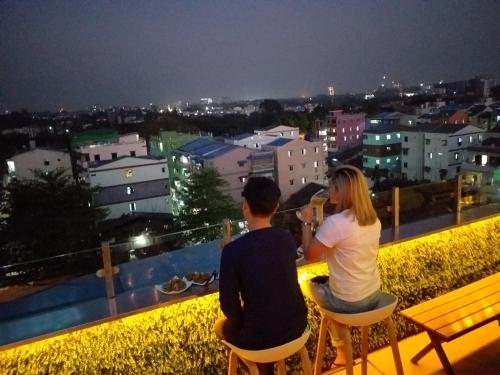 two people sitting on a balcony looking at the city at night at Hotel Broadway Yangon in Yangon