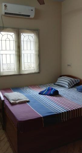ein großes Bett in einem Schlafzimmer mit zwei Fenstern in der Unterkunft Atreyaa Homestay in Tiruchchirāppalli