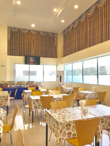 a dining room with tables and chairs and windows at Hotel Broadway Yangon in Yangon