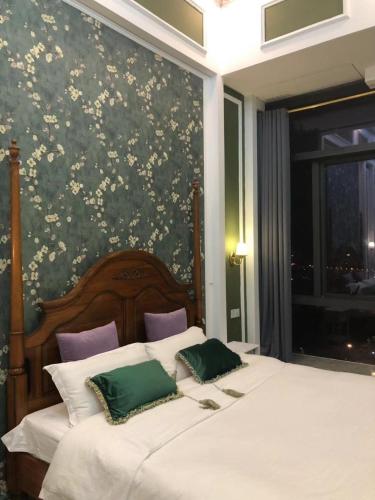 a bedroom with a large bed with green and white pillows at April Fair Duplex Apartment Guangzhou South Railway Station Ao Yuan Yue Shi Dai Branch in Guangzhou