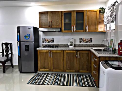 a kitchen with wooden cabinets and a stainless steel refrigerator at Fully Equipped New 1br Apt–dt–2mins To Beach in Sosúa