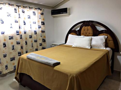 a bedroom with a large bed with a wooden headboard at Fully Equipped New 1br Apt–dt–2mins To Beach in Sosúa