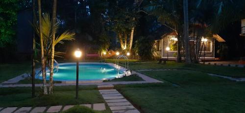 a swimming pool in a yard at night at Orchid Trails Resort in Sultan Bathery
