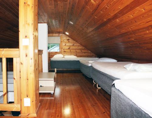 Habitación con 3 camas en una cabaña de madera en Tervakosken Tervaniemi hirsimökki & oma sauna, en Tervakoski