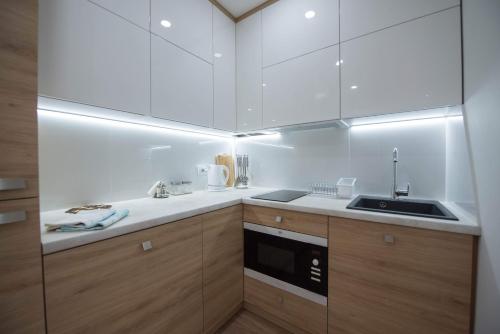 a kitchen with white cabinets and a sink at Затишні апартаменти вул Глибока 24 in Ternopilʼ