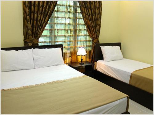 Habitación de hotel con 2 camas y ventana en Villasuri Homestay en Kuantan