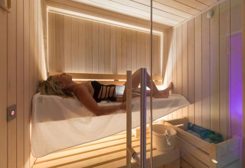 a woman laying in a bath tub in a sauna at Masseria La Tofala benessere & SPA in Copertino