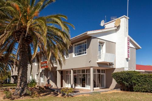 a white building with a palm tree in front of it at Loganda Karoo Lodge in Touwsrivier