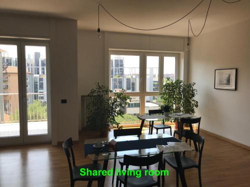 una sala da pranzo con tavoli, sedie e finestre di Feel@Home Apartment+Rooms a Milano