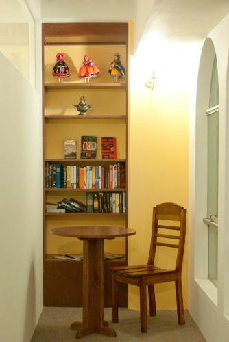 a table and a chair next to a book shelf at Hotel Munay Tambo in Puno