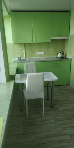 eine Küche mit einem Tisch, Stühlen und grünen Schränken in der Unterkunft Студія з сучасним ремонтом in Kiew