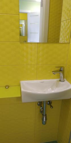 ein weißes Waschbecken im gelben Badezimmer mit Spiegel in der Unterkunft Студія з сучасним ремонтом in Kiew