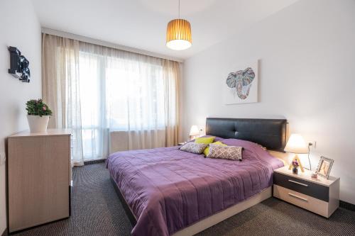 a bedroom with a purple bed and a window at NC Apartment Ruse in Ruse