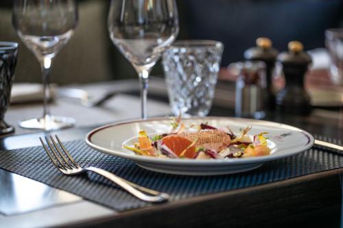 a plate of food on a table with wine glasses at La Maison d'Estournel in Saint-Estèphe