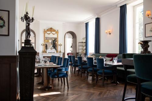 a dining room with tables and blue chairs at La Maison d'Estournel in Saint-Estèphe
