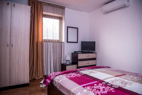 a bedroom with a bed and a tv and a window at EUROPE GUEST HOUSE § КЪЩА ЗА ГОСТИ ЕВРОПА in Veliko Tŭrnovo