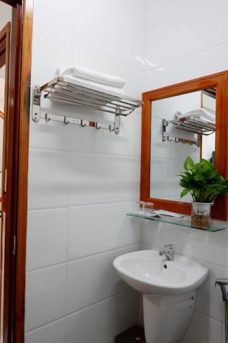 a white bathroom with a sink and a mirror at Thy Hung legacy hotel in Tuy Hoa