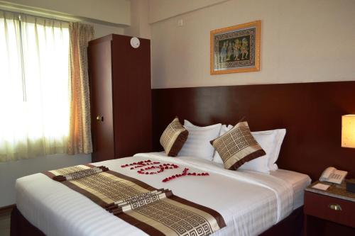 a bedroom with a large bed with red flowers on it at Hotel Broadway Yangon in Yangon