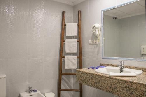 a bathroom with a sink and a mirror and a toilet at Hospedium Hotel Don Jose in Castalla