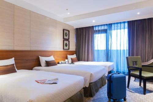 a hotel room with two beds and a suitcase at Pacific Business Hotel in Taipei