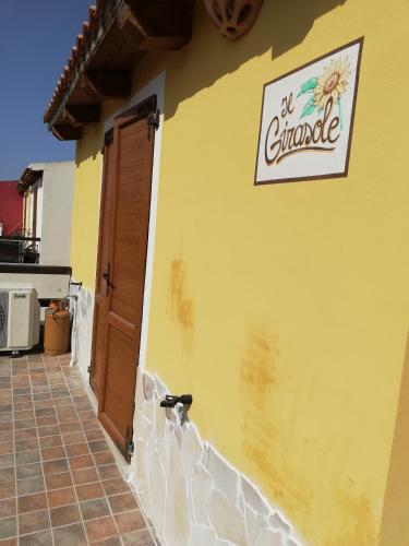 a yellow building with a sign on the side of it at Апартаменты с великолепным видом на горы in Viddalba