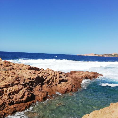 a rocky beach with the ocean in the background at Апартаменты с великолепным видом на горы in Viddalba