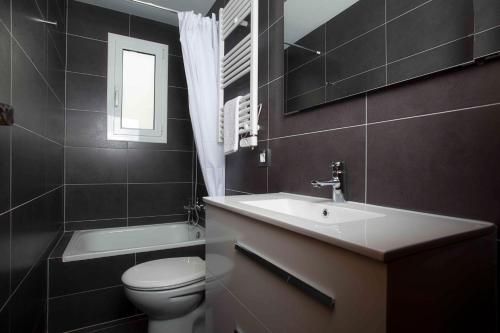 a bathroom with a sink and a toilet and a mirror at Apartamentos Sunway Talaia in Sitges