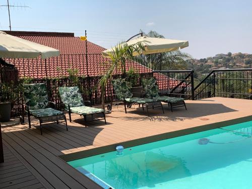 a swimming pool with chairs and umbrellas on a deck at Bokamoso Views in Rustenburg