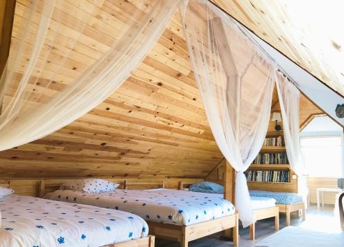 two beds in a room with a wooden ceiling at Guest House Gravas in Bauska