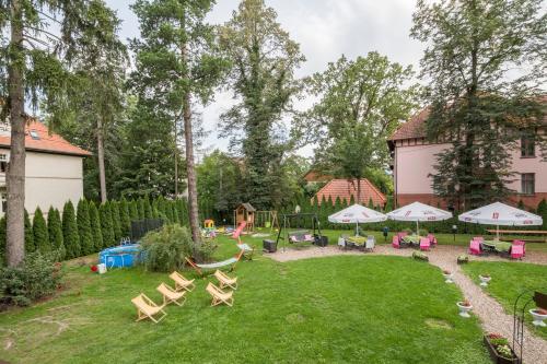 a yard with a playground with chairs and umbrellas at Hotel Bella in Jelenia Góra