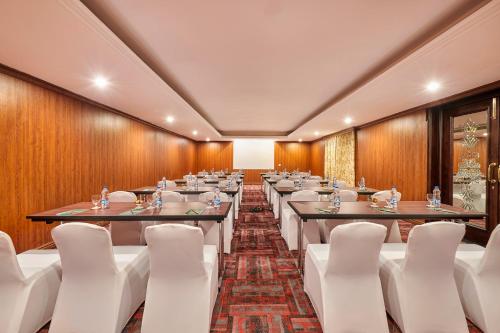 a conference room with tables and white chairs at MAYFAIR Lake Resort in Raipur