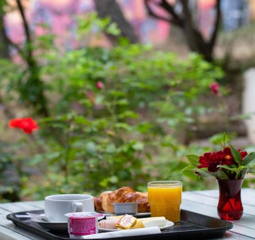 a tray with breakfast foods and a glass of orange juice at Hotel CIS Paris Kellermann in Paris