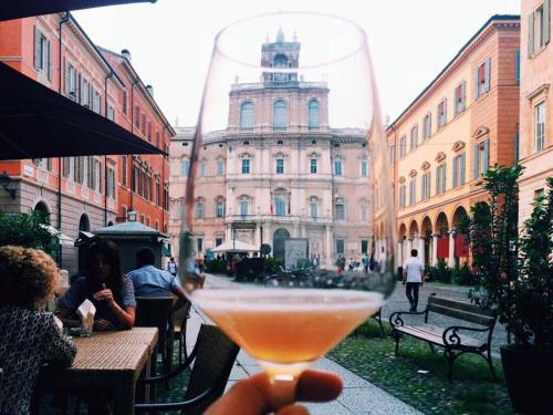una persona che tiene un drink di fronte a un edificio di La casa del Centro a Modena