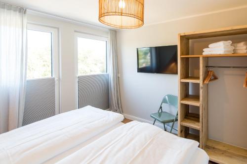 a bedroom with a bed and a tv and two windows at Welle 11 Sylt in Westerland