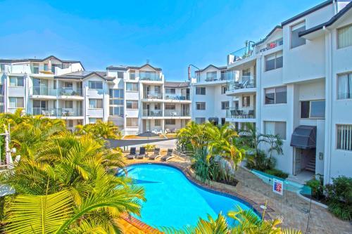 uma imagem de um complexo de apartamentos com uma piscina e palmeiras em Sandcastles On Currumbin Beach em Gold Coast