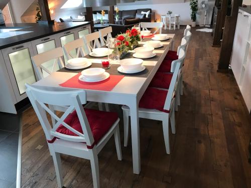 a white dining room table with white chairs and red napkins at Wieko Ferienwohnungen - Luxus Pur im Prinz von Preußen in Bad Elster