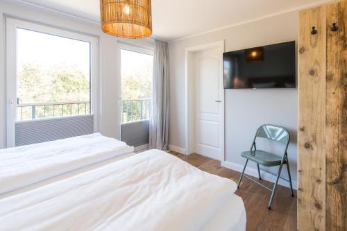 a bedroom with a bed and a chair and a window at Welle 11 Sylt in Westerland (Sylt)