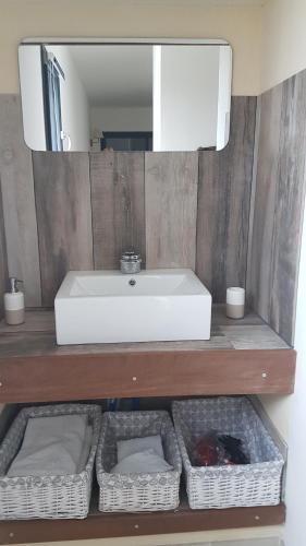 ein Badezimmer mit einem Waschbecken, einem Spiegel und Körben in der Unterkunft Superbe appartement avec 3 chambres vue mer in Propriano