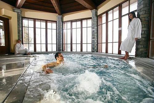 アーク 1950にあるARC 1950 appartement 716 Manoir de Savoieの温水浴槽に浸かっている男性とそこに立っている女性